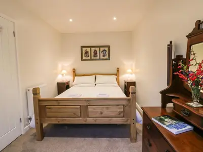 a bedroom with a bed and a wooden dresser at The Coach House in Bodmin