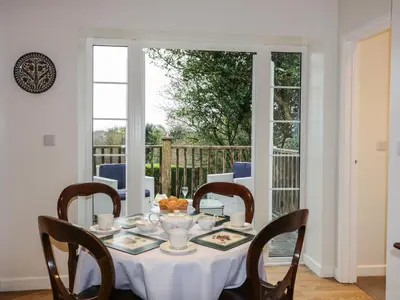 a dining room table with a white table cloth and chairs at The Coach House in Bodmin