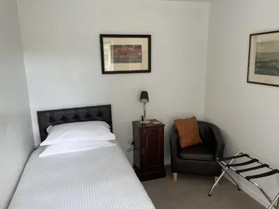 a bedroom with a bed and a chair at The Coach House in Bodmin