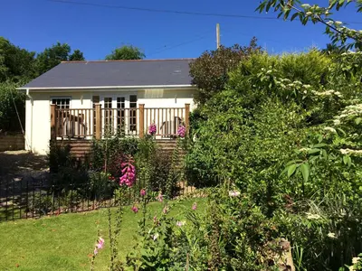 a small white house with a fence and flowers at The Coach House in Bodmin