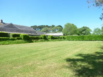 a large grass field with a house in the background at The Granary in Saint Erth