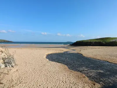 a sandy beach with a stream of water at Rockpool in Padstow
