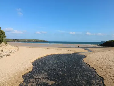a beach with a large shadow on the sand at Rockpool in Padstow