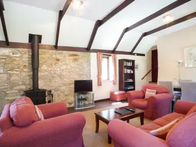 a living room with red chairs and a fireplace at Parlour Cottage in Saint Erth