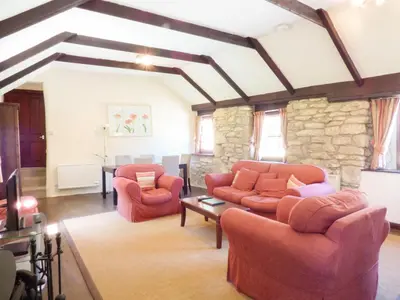 a living room with two couches and a stone wall at Parlour Cottage in Saint Erth