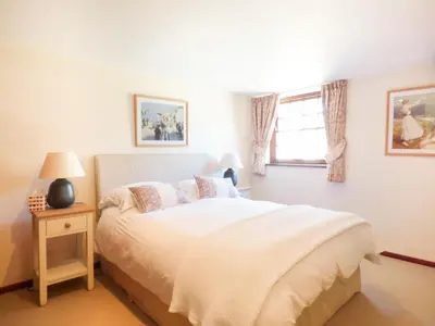 a bedroom with a white bed and a window at Parlour Cottage in Saint Erth