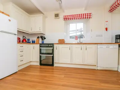 a kitchen with white appliances and a wooden floor at Goshen Farm in St. Agnes