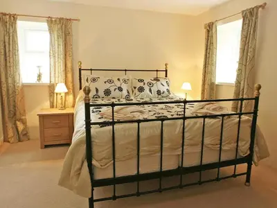 a bedroom with a bed and two windows at Godrevy Cottage in Hayle