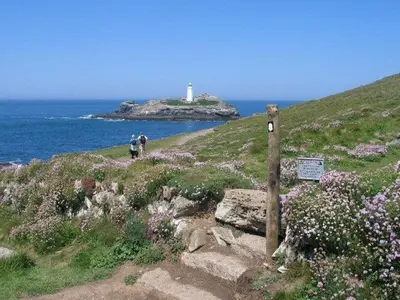 two people walking up a hill with a lighthouse at Godrevy Cottage in Hayle