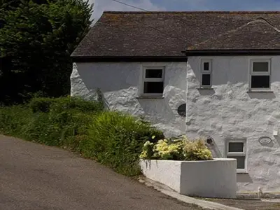 a white house with a flower pot in front of it at Godrevy Cottage in Hayle