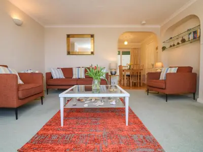 a living room with a white coffee table on a red rug at Sea Star in Porthleven