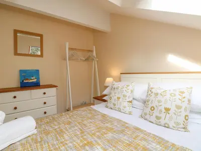 a bedroom with a white bed and a dresser at Sea Star in Porthleven