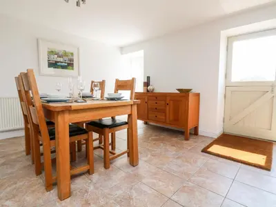 a dining room with a wooden table and chairs at Black Rock in St Austell