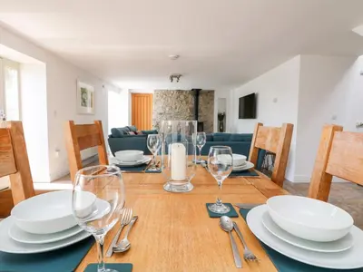 a dining room with a wooden table with plates and wine glasses at Black Rock in St Austell