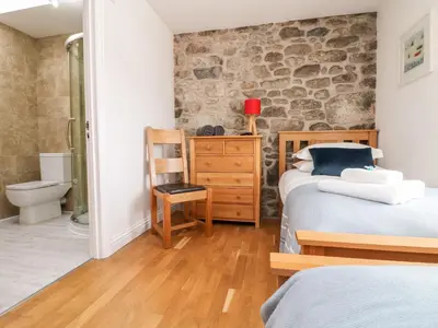 a bedroom with two beds and a stone wall at Black Rock in St Austell