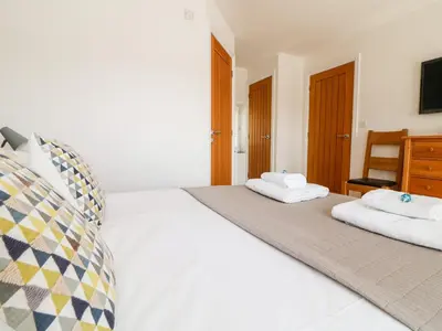 a bedroom with a white bed with two towels on it at Black Rock in St Austell