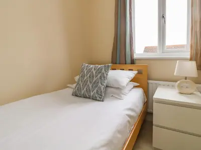 a bedroom with a bed with white sheets and a window at Pentewan in Hayle