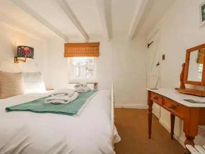 a bedroom with a bed and a sink and a mirror at Trehan in St Ives
