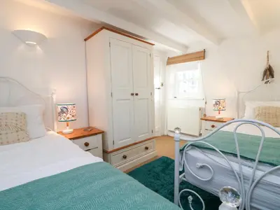a bedroom with a white bed and a green rug at Trehan in St Ives