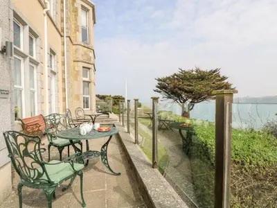 a table and chairs on a balcony with a view of the water at By The Sea in Newquay
