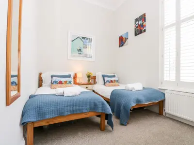 a room with two beds and a table and windows at By The Sea in Newquay