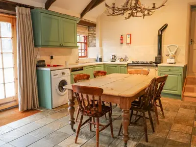 a kitchen with green cabinets and a wooden table and chairs at Barn Cottage in Saint Erth