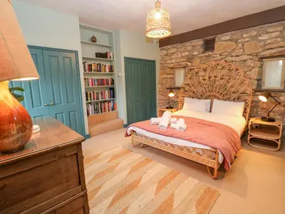 a bedroom with a large bed with a stone wall at Barn Cottage in Saint Erth