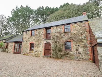 an old stone house with red doors and windows at Barn Cottage in Saint Erth