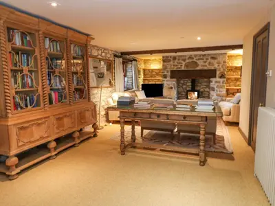 a living room with a table and a stone fireplace at Barn Cottage in Saint Erth