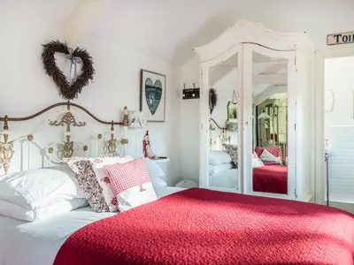 a bedroom with a bed with a red blanket and a mirror at The Snug in Bugle