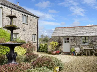 a stone cottage with a garden and a fountain at The Snug in Bugle