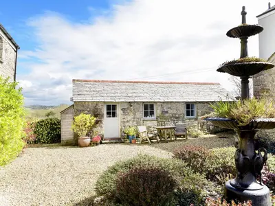a stone cottage with a fountain in front of it at The Snug in Bugle
