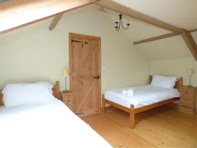 a bedroom with two beds and a door in a attic at Meadow Cottage in Fowey
