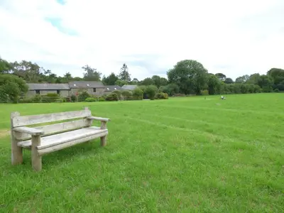 a wooden bench sitting in a field of grass at Meadow Cottage in Fowey
