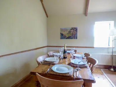 a dining room with a wooden table and chairs at Meadow Cottage in Fowey