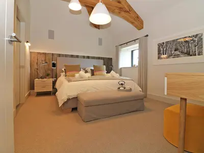 a bedroom with a large bed and a table at Mill House, Boskensoe Barns in Falmouth