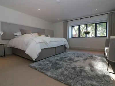 a bedroom with a bed and a large window at Mill House, Boskensoe Barns in Falmouth