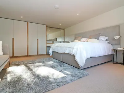 a bedroom with a large bed and a rug at Mill House, Boskensoe Barns in Falmouth