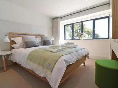 a bedroom with a large bed and a window at Mill House, Boskensoe Barns in Falmouth