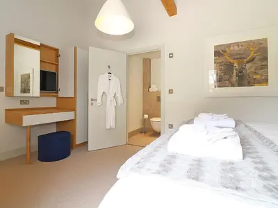 a bedroom with a white bed and a bathroom at The Stable, Boskensoe Barns in Falmouth
