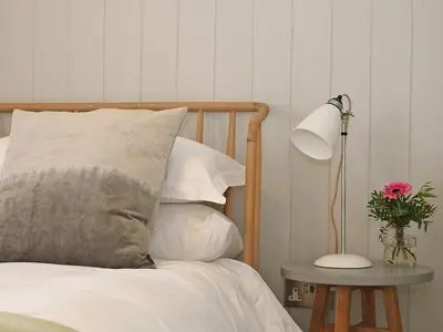 a bed with white pillows and a table with a lamp at The Stable, Boskensoe Barns in Falmouth