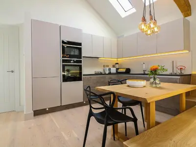 a kitchen with a wooden table and chairs and a dining room at The Stable, Boskensoe Barns in Falmouth