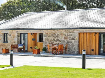a stone cottage with a table and chairs in front of it at The Stable, Boskensoe Barns in Falmouth
