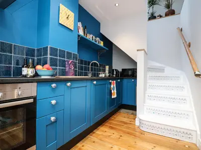 a kitchen with blue cabinets and blue tiles at The Snug in Grampound