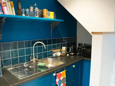 a kitchen with a sink and a blue wall at The Snug in Grampound