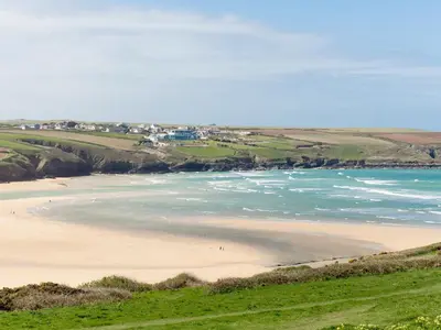 a beach with people walking on the sand and the water at Cribbar View in Newquay