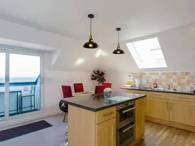 a kitchen with wooden cabinets and a large window at Cribbar View in Newquay