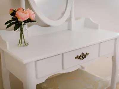 a white vanity with a vase of flowers and a mirror at Cribbar View in Newquay
