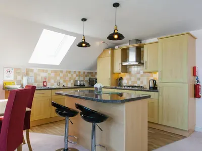 a kitchen with wooden cabinets and a island with bar stools at Cribbar View in Newquay