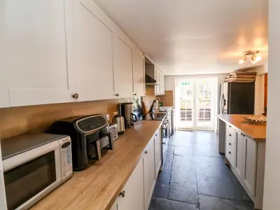 a kitchen with white cabinets and a wooden counter top at Tower House in Boscastle